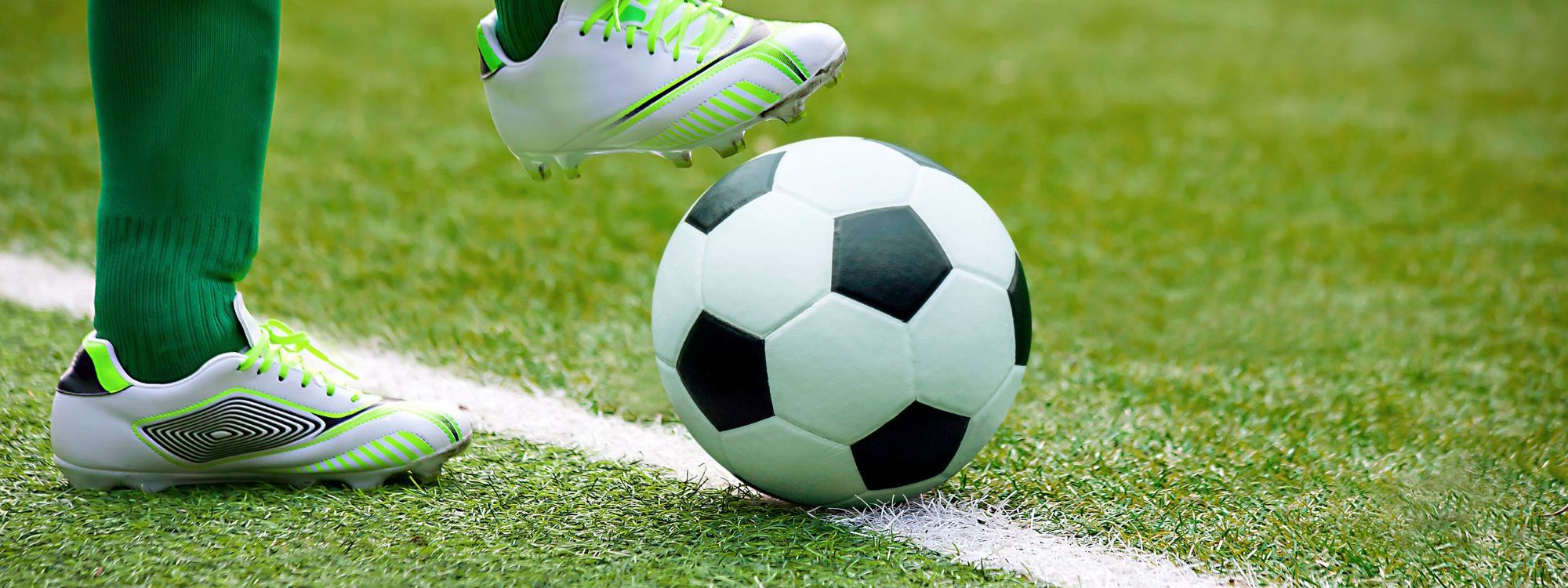 Football player with ball on Astro turf pitch