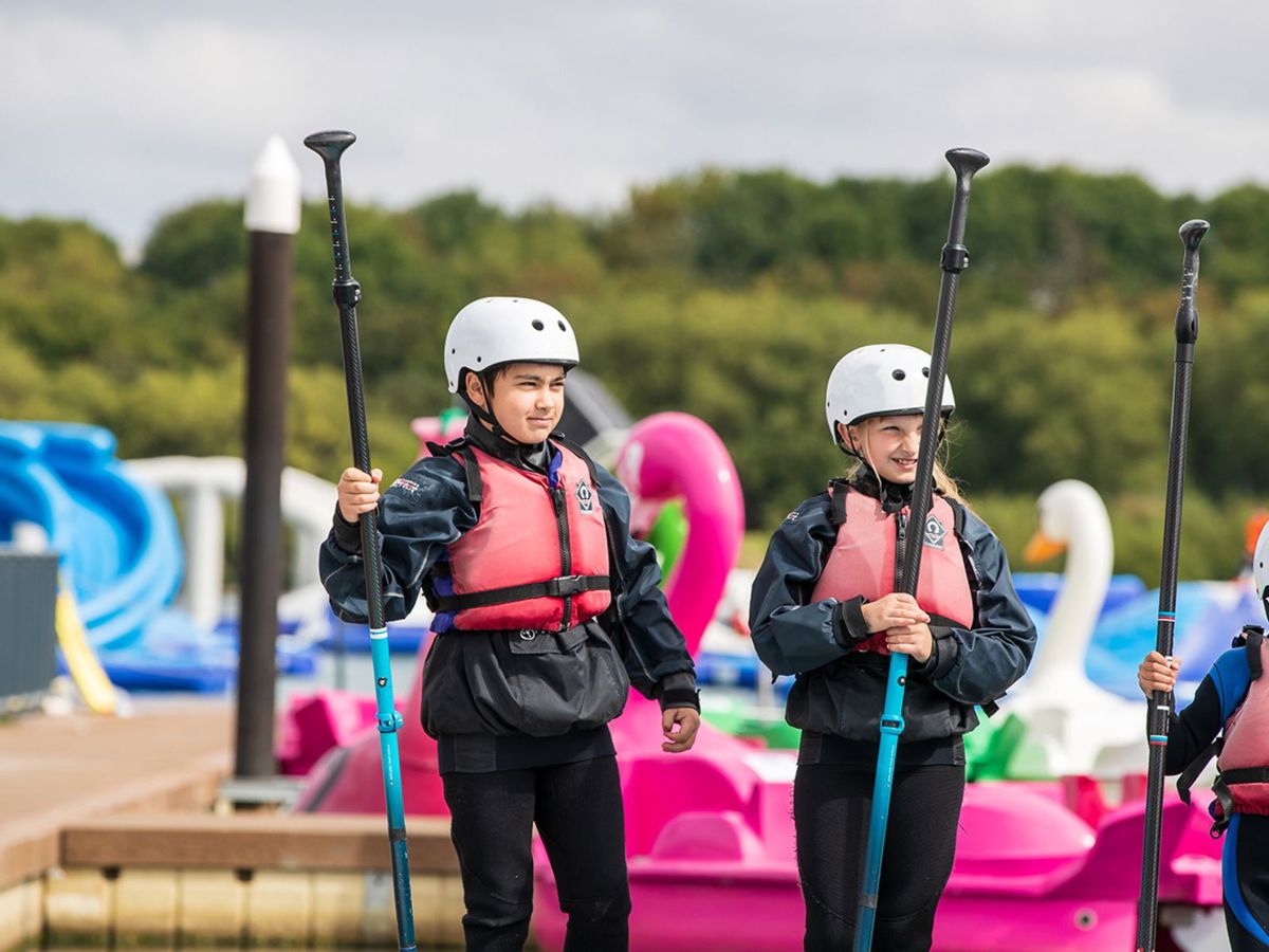 Children holding paddles for watersports session