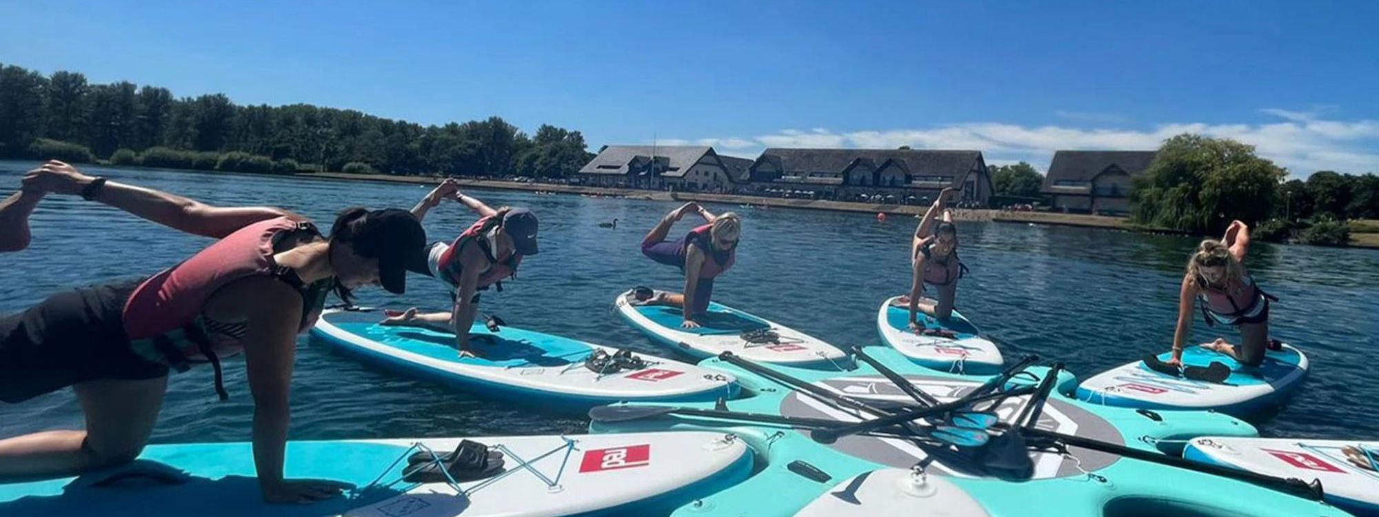 People doing yoga pose on paddleboards on Willen Lake