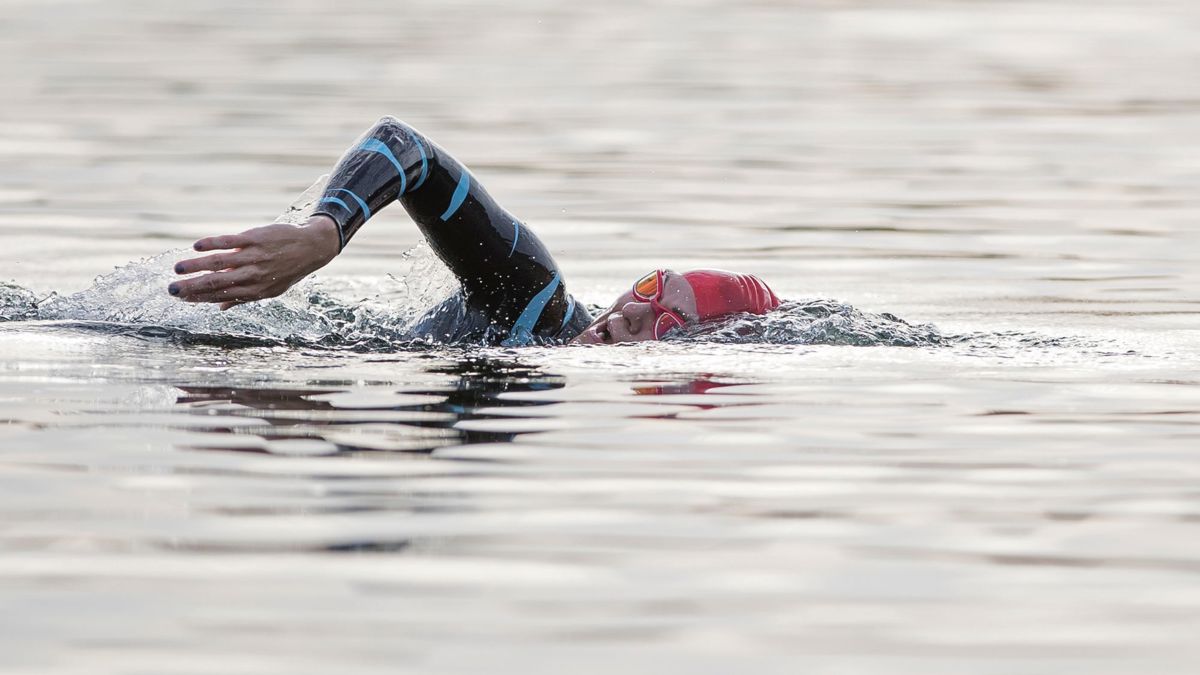 Person swimming in wetsuit and cap swimming in the lake