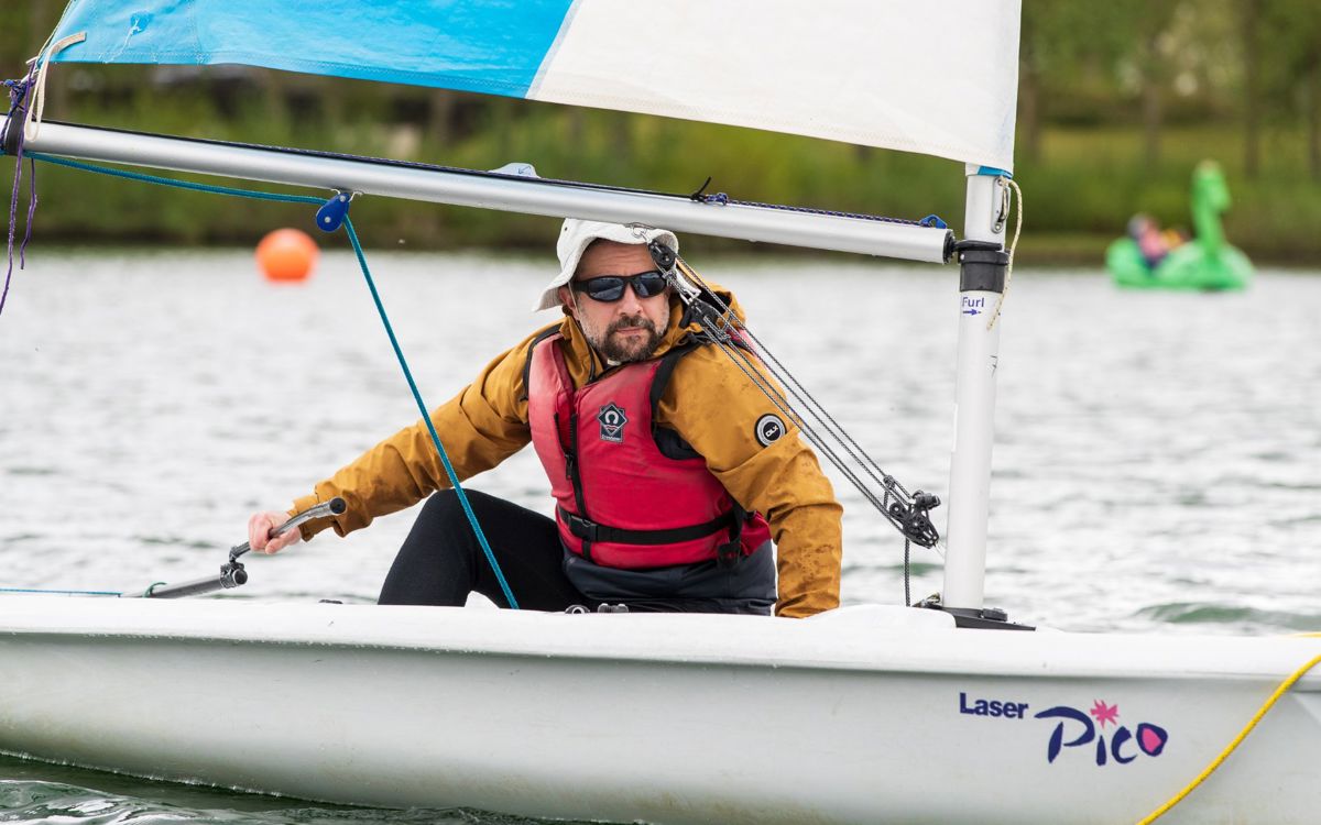 Person navigating sailing boat on a lake