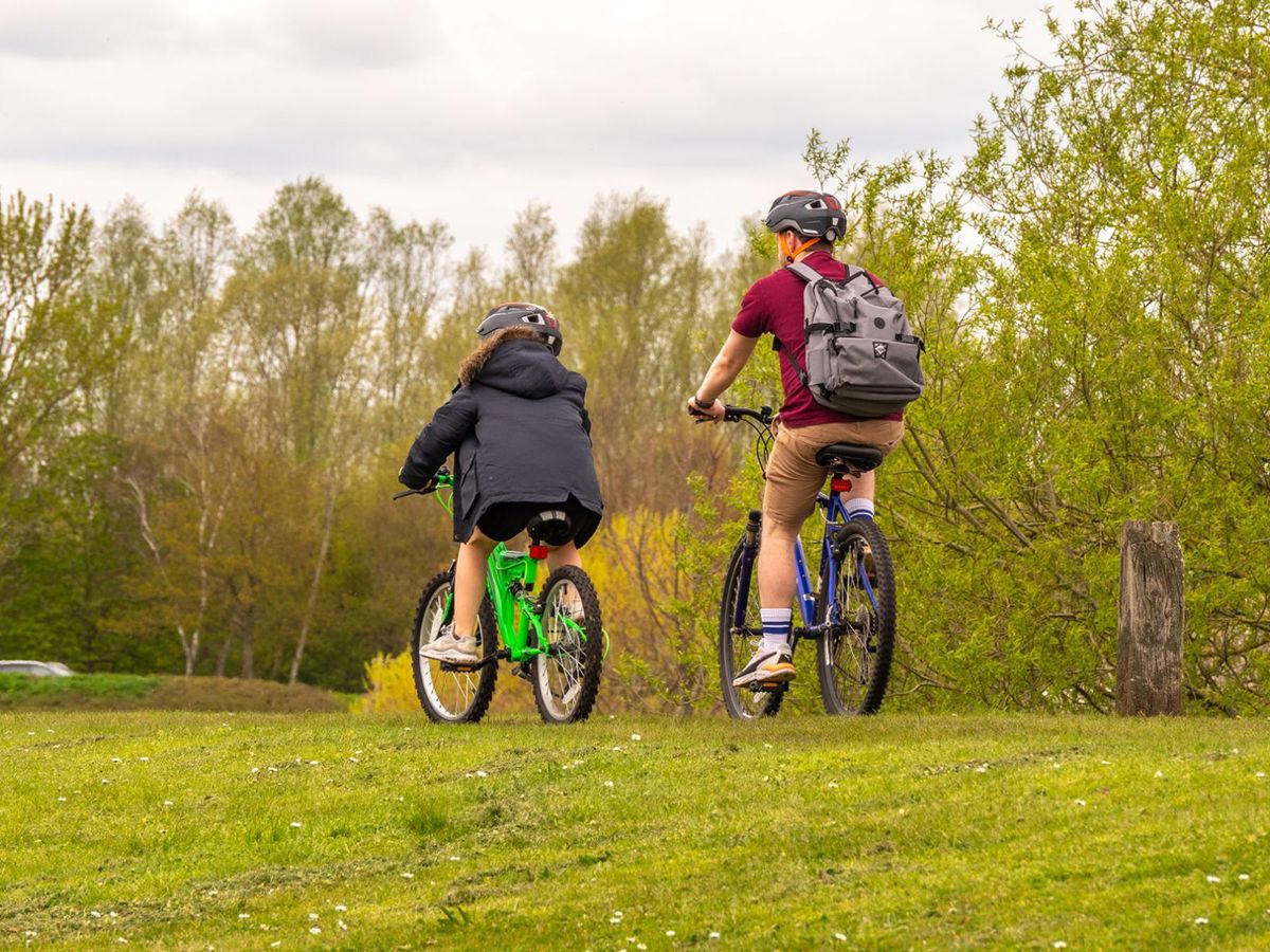 Two people cycling around Willen Lake with trees in the background