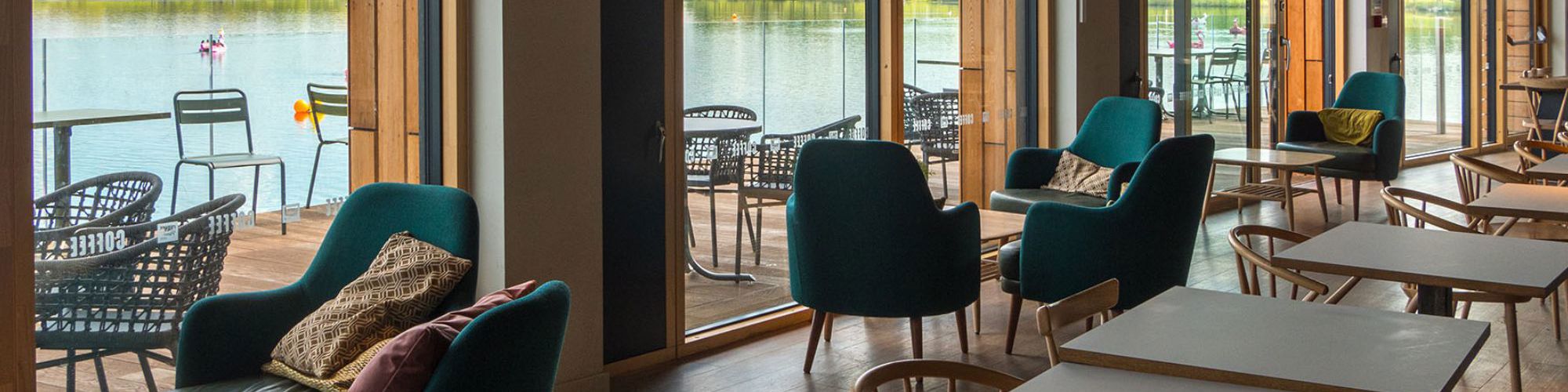 Inside of Willen Lake cafe showing tables and chairs and view across the lake