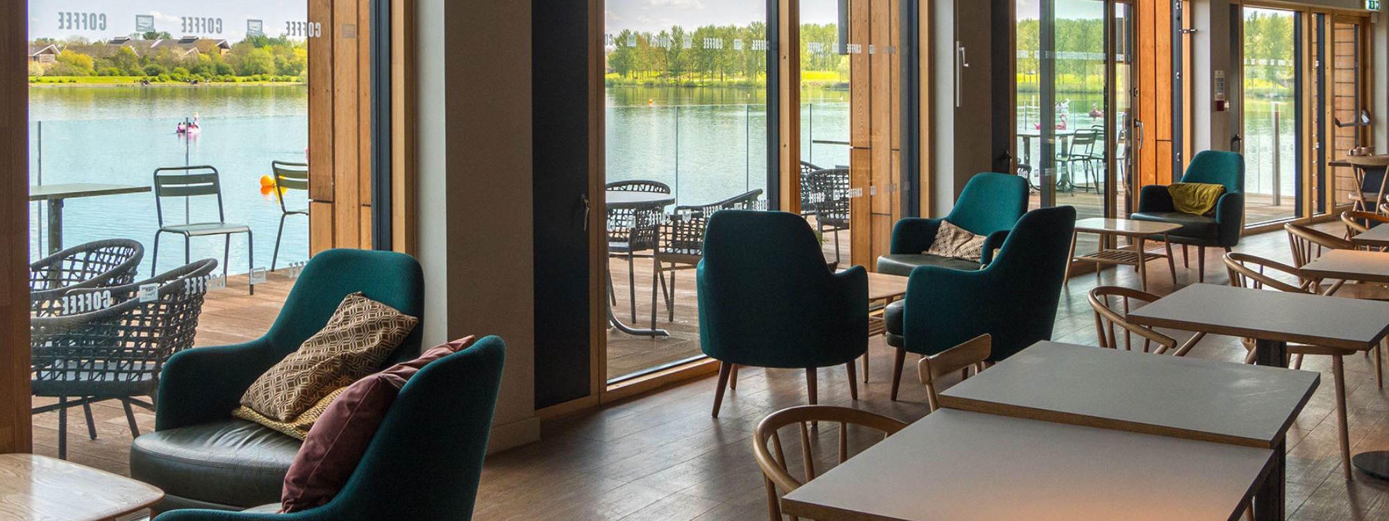 Inside of Willen Lake cafe showing tables and chairs and view across the lake