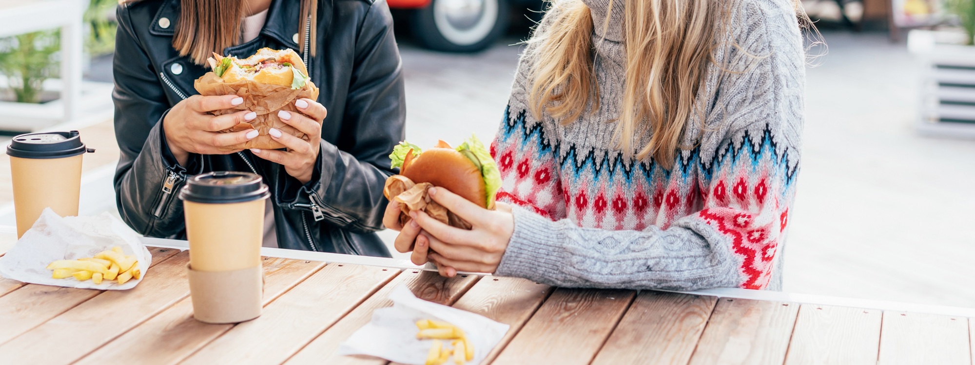 Two people sat at a table eating a burger at a street food event