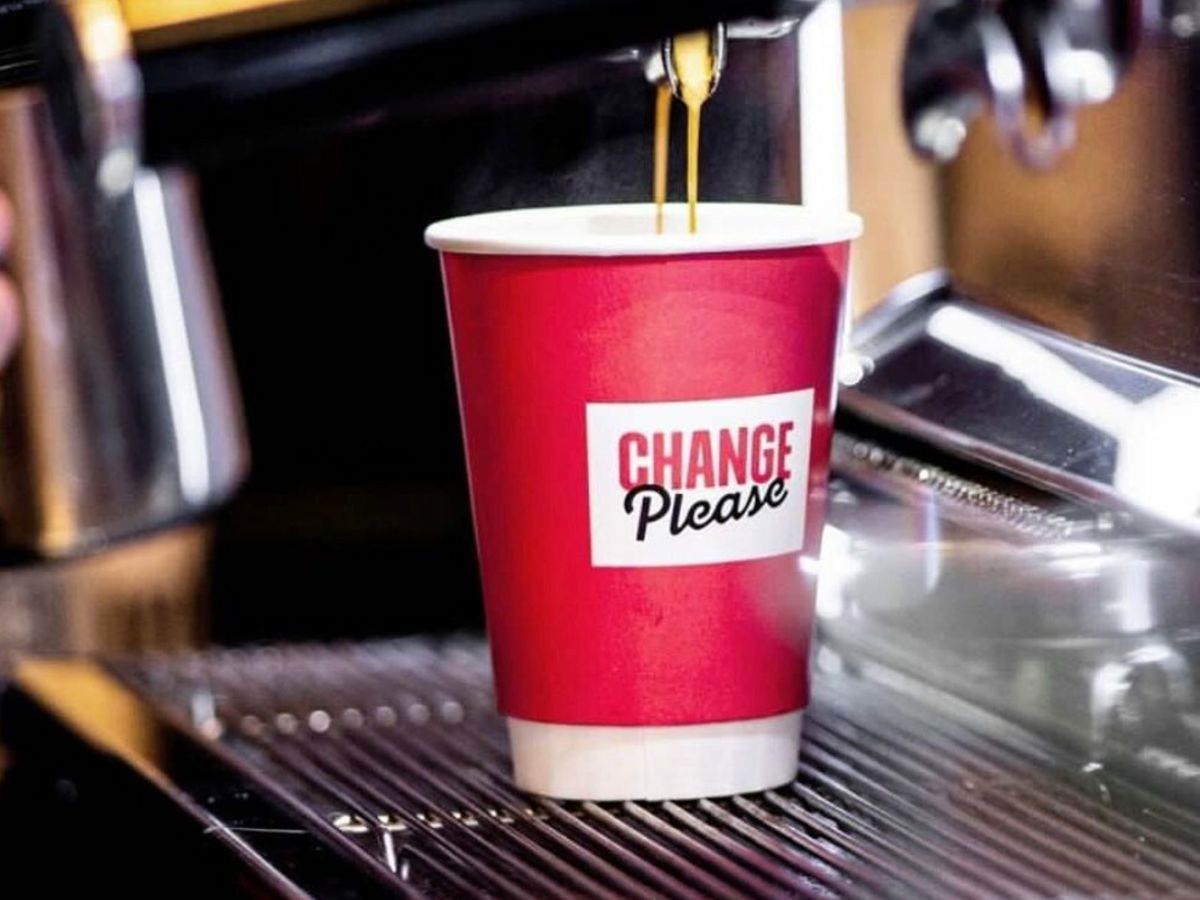 Cup with Change Please logo under dripping coffee machine