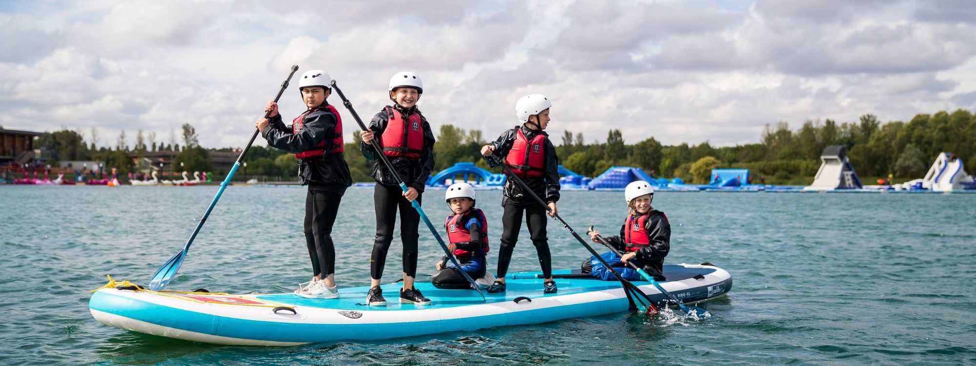 Group of children holding paddles on SUP board