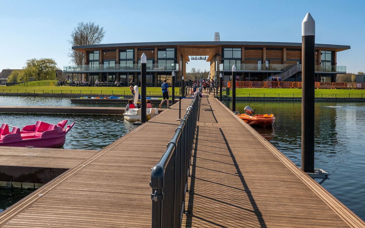 People walking on the jetty next to pedalos outside the front of the watersports centre