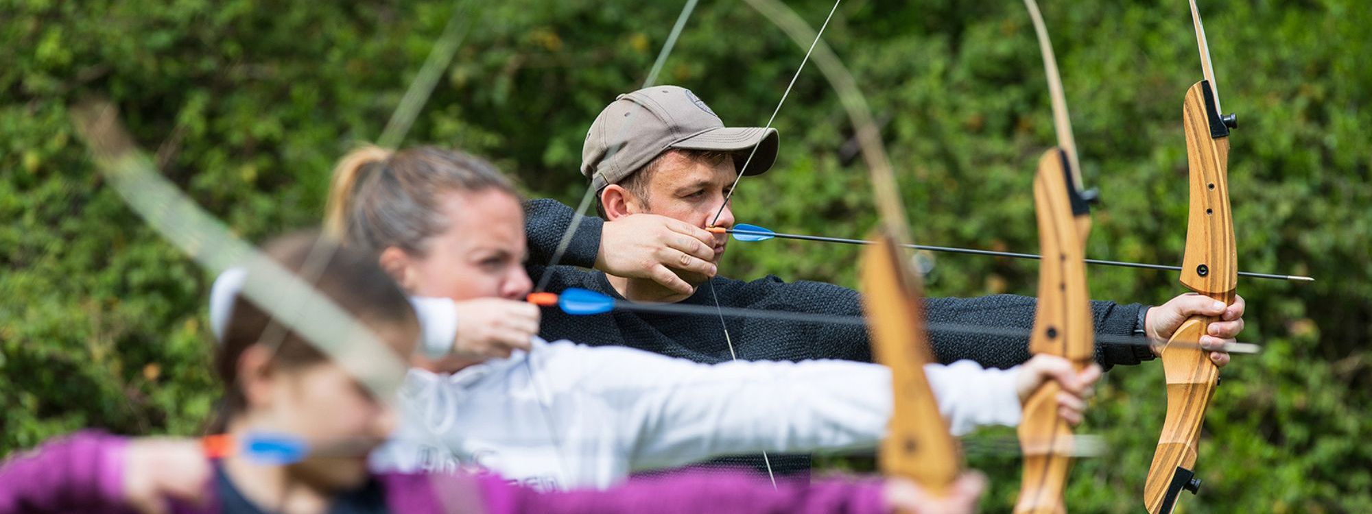 Three people aiming at an archery session